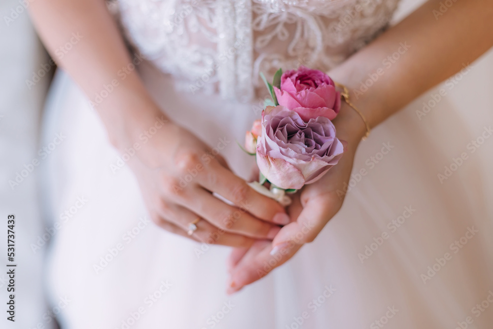 The bride holds a boutonniere for the groom on the wedding day. The bride holds a boutonniere for the groom on the wedding day.