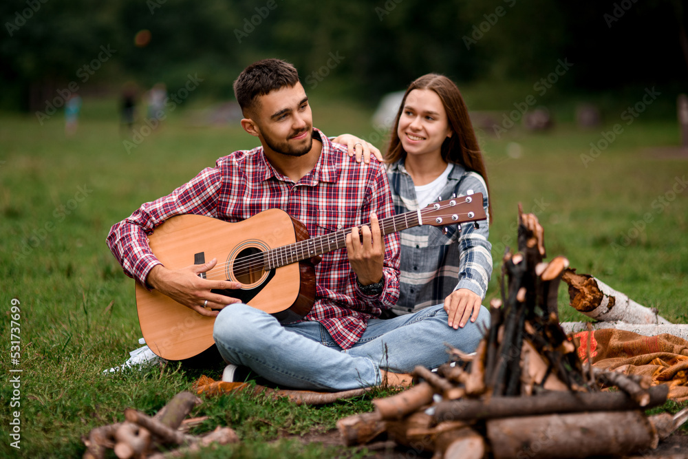 beautiful couple with guitar spending time together at park. Love story.