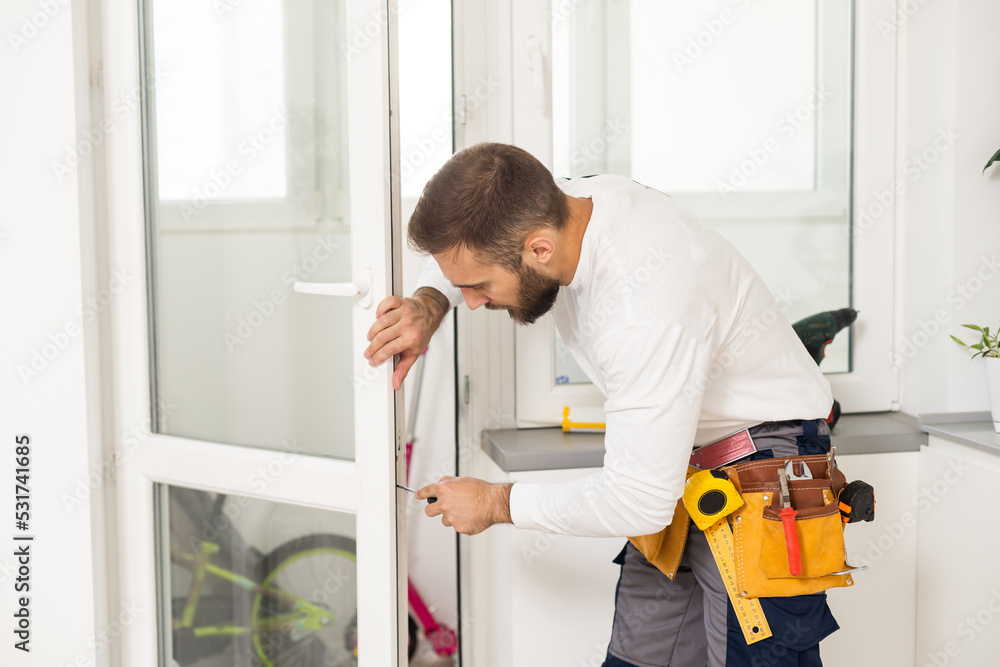 service man installing window with screwdriver