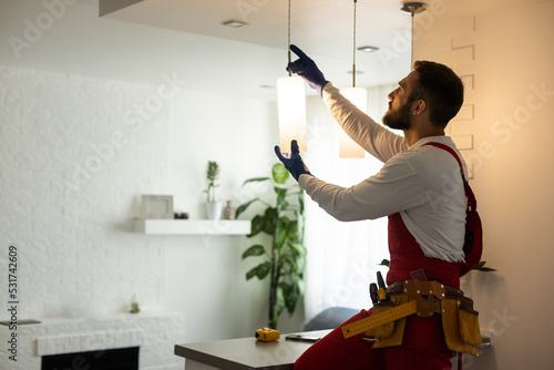 electrician installing led light bulbs in ceiling lamp photo