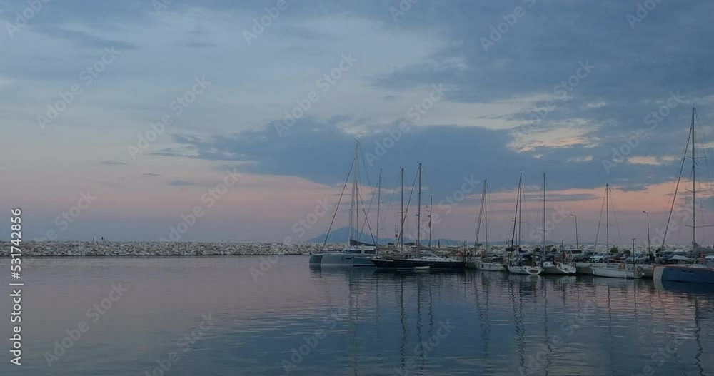 Sailboats and yachts in the boat marina at sunset. Beautiful sky with clouds in dusk. Summertime holidays landscape. Sailboats and yachts in the boat marina at sunset. Beautiful sky with clouds in dusk. Summertime holidays landscape.