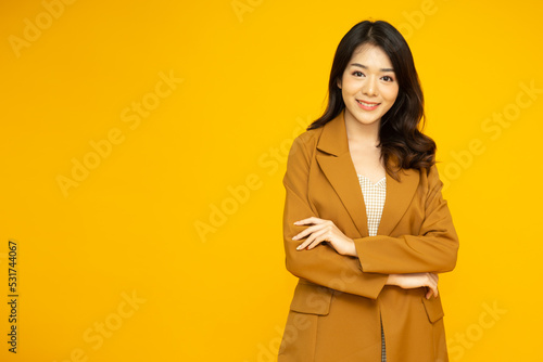 Young Asian business woman smiling with arms crossed isolated on yellow background © comzeal