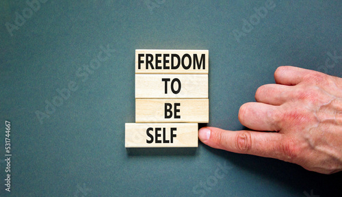 Freedom to be self symbol. Concept words Freedom to be self on wooden blocks on a beautiful grey table grey background. Businessman hand. Business, psychological freedom to be self concept.