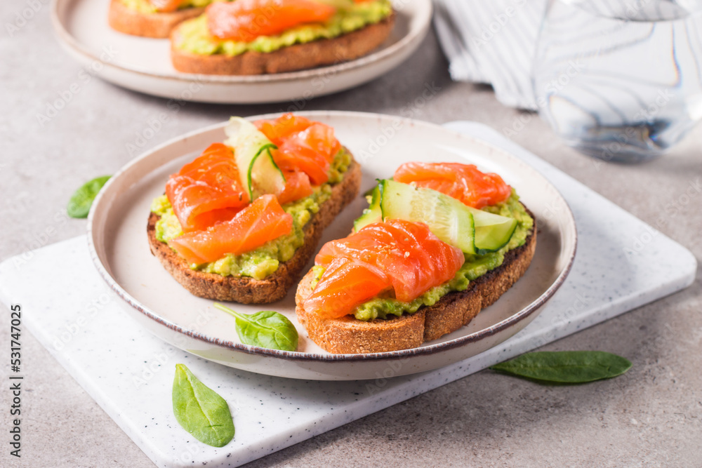 Open sandwich with smoked and salted salmon for healthy breakfast. Trout and avocado on bruschetta toast. Open sandwich with smoked and salted salmon for healthy breakfast. Trout and avocado on bruschetta toast.