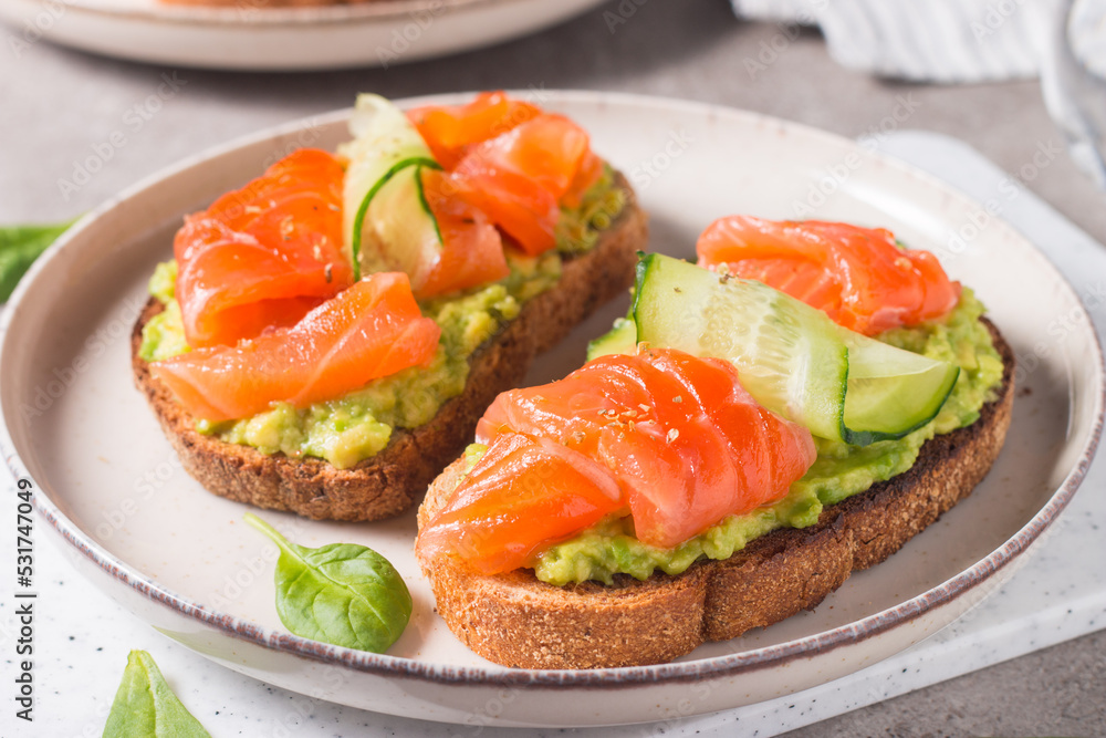Open sandwich with smoked and salted salmon for healthy breakfast. Trout and avocado on bruschetta toast. Open sandwich with smoked and salted salmon for healthy breakfast. Trout and avocado on bruschetta toast.