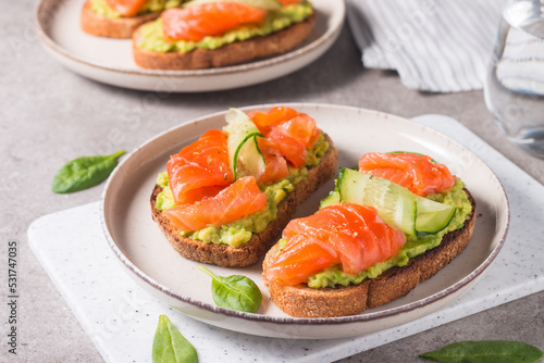 Open sandwich with smoked and salted salmon for healthy breakfast. Trout and avocado on bruschetta toast. 