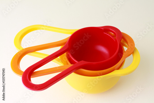 Colorful plastic measuring spoons and measuring cups on bright background