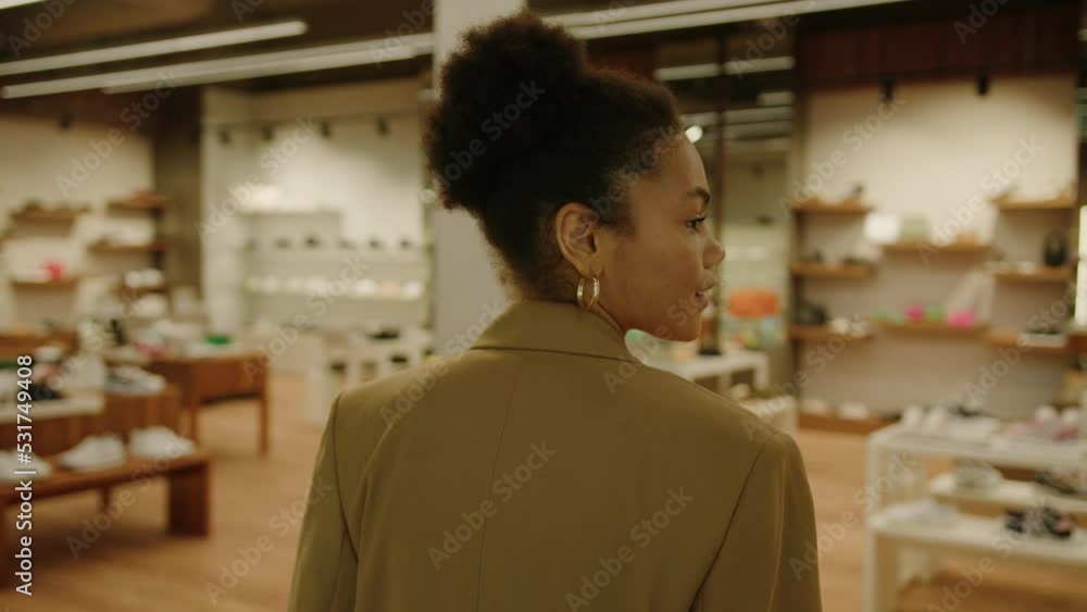 A stylish African-American woman in a jacket walks into a luxury shoe store A stylish African-American woman in a jacket walks into a luxury shoe store