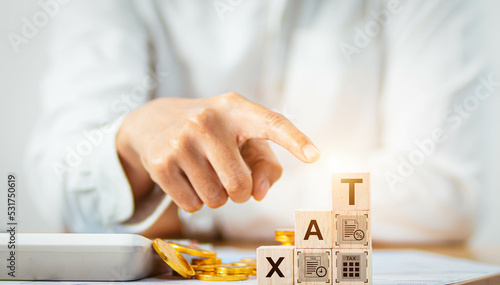  Businessman pointing his finger at a wooden cube Composed of letters: taxes, taxation concepts, finance, investments