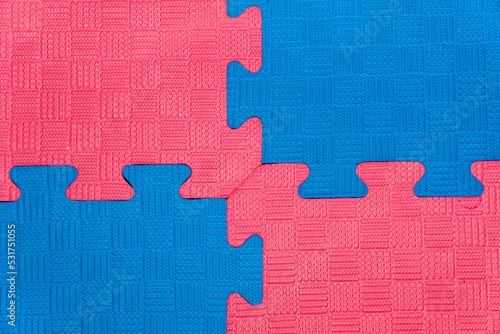 Eva foam rubber floor puzzle mats texture, colorful floor mat background. Multicolored soft elements. Blue and pink puzzles connected