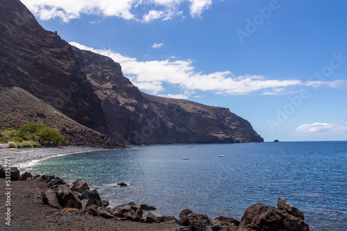 Scenic coastal hiking trail to Playas de las Arenas along massive cliffs in Valle Gran Rey on La Gomera, Canary Islands, Spain, Europe. Path leads to peak of Teguergenche. One boat in remote lagoon photo