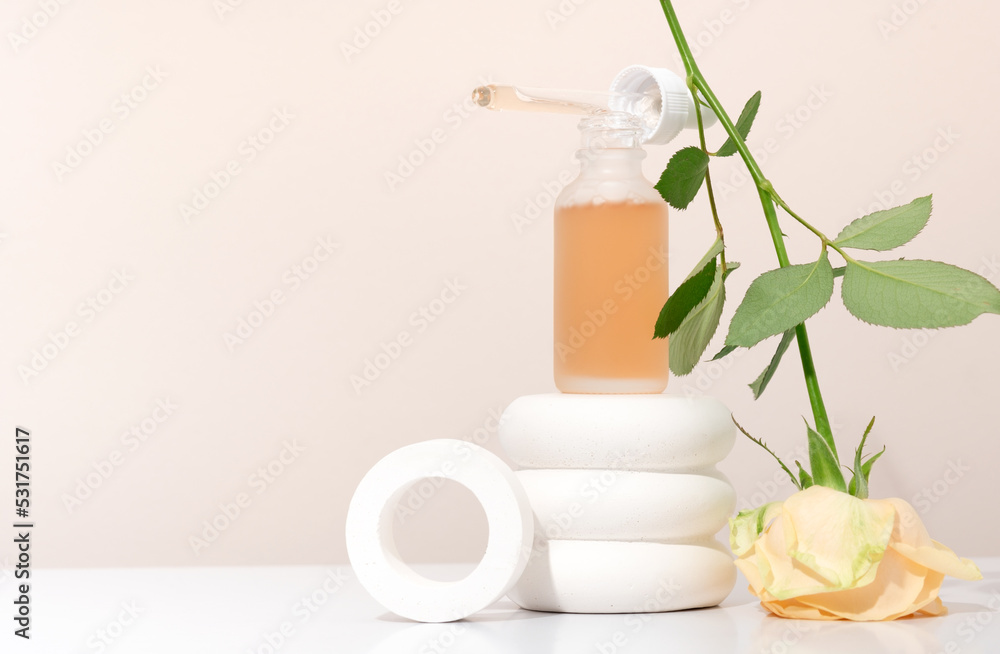 Mockup cosmetics serum with a pipette in a transparent frosted glass and orange liquid. Facial peeling with lactic Aha acid on a white pedestal, beige background with roses Mockup cosmetics serum with a pipette in a transparent frosted glass and orange liquid. Facial peeling with lactic Aha acid on a white pedestal, beige background with roses