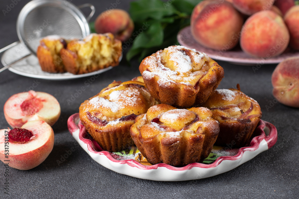 Homemade tasty muffins with peaches on plate on gray background