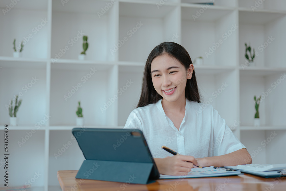 Businesswoman working on tablet and laptop in office with happy face. Businesswoman working on tablet and laptop in office with happy face.