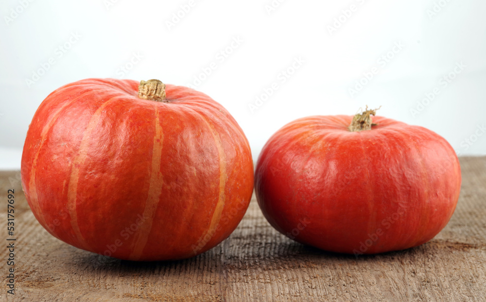 Red kuri squashes on a rough woody texture background. Selective focus. Red kuri squashes on a rough woody texture background. Selective focus.