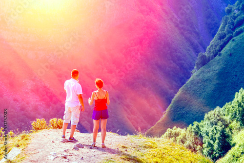 A tourist watches the setting sun in the mountains. Beautiful mountains, breathtaking view. A couple on a journey looks at the majestic mountains. Travel and active lifestyle
