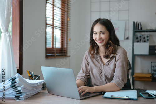 Young business woman working and typing on laptop with happy and smile face on office space.