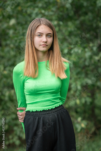 Portrait of a young beautiful girl in a green blouse and black parka pants.