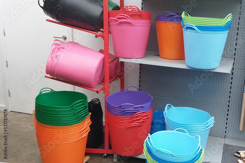 Buckets and laundry baskets made of soft plastic in different colors on sale in a hardware store