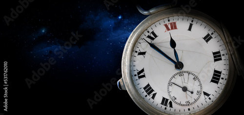 An old antique clock with roman numerals on the dial and clockwork. Isolated on night starry sky