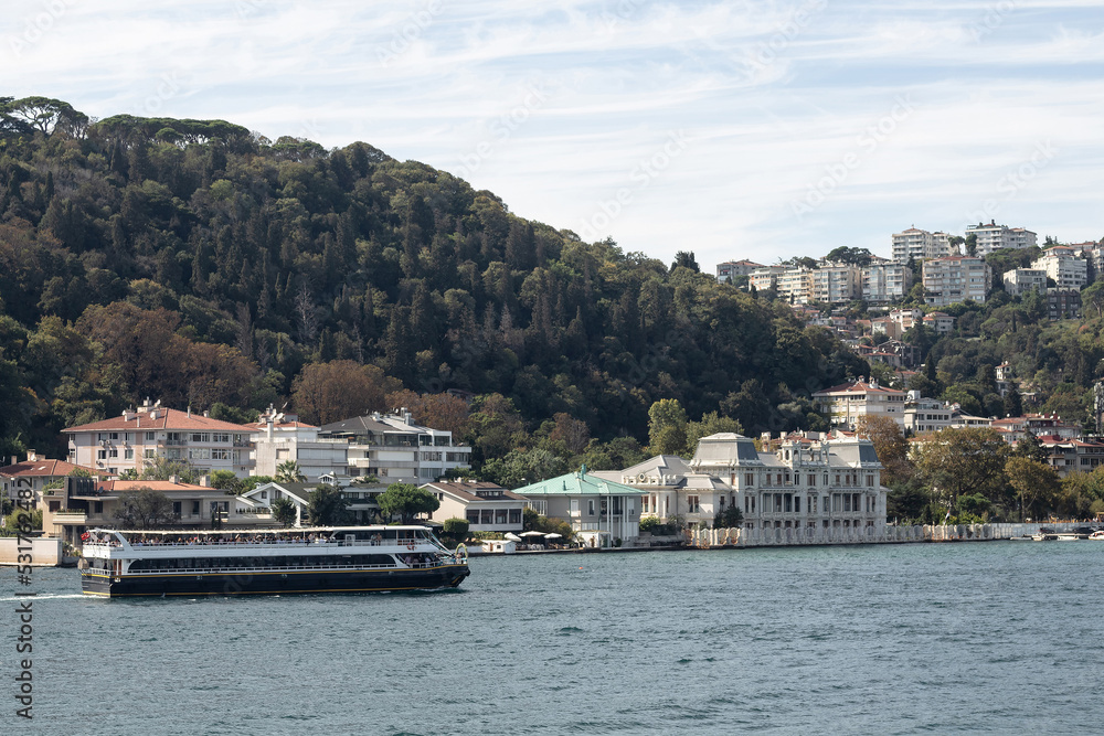 Naklejka premium View of a cruise tour yacht on Bosphorus and Bebek neighborhood on European side of Istanbul. It is a sunny summer day. Beautiful travel scene.
