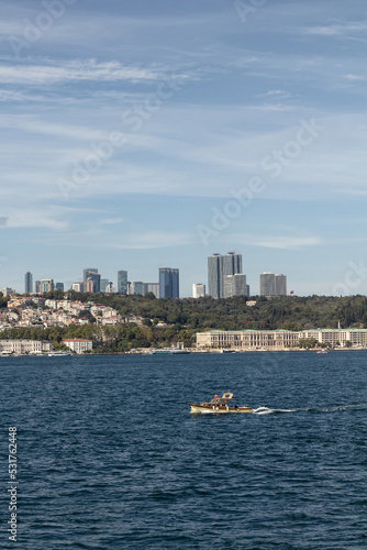 View of small, wooden fishing boat on Bosphorus and European side of Istanbul. It is a sunny summer day.