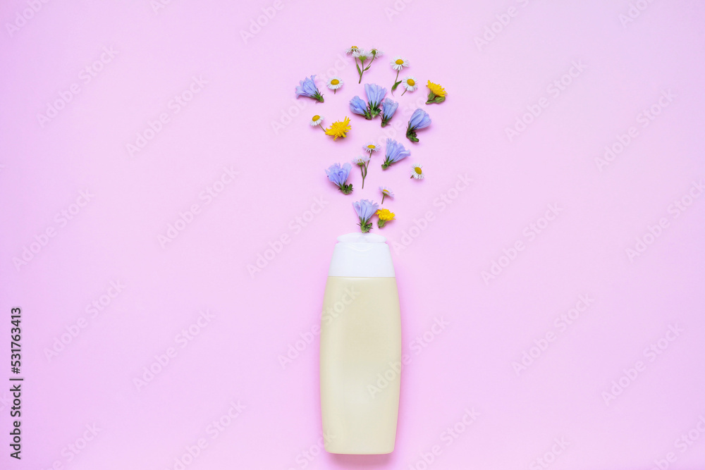 Yellow bottle with flowers on colorful pink background in minimal style top view flat lay with space for text copy space. bio organic eco natural product beauty and spa