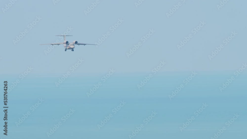 Long shot plane flies over the sea, landing down. Unrecognizable airliner flies against the background of the sea. Tourism and travel concept Long shot plane flies over the sea, landing down. Unrecognizable airliner flies against the background of the sea. Tourism and travel concept