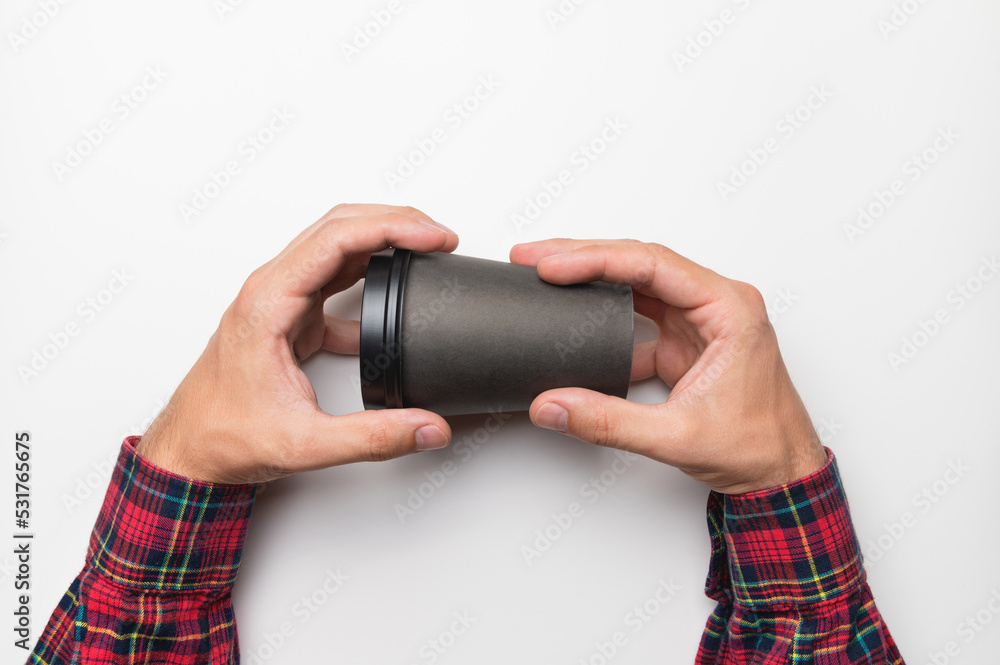 male hands in a plaid shirt hold a paper glass with a hot drink, with a place for an inscription, on a white background. studio shot male hands in a plaid shirt hold a paper glass with a hot drink, with a place for an inscription, on a white background. studio shot