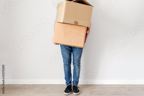 Un hombre joven sujetando dos cajas de cartón. Sin mostrar el rostro. Concepto de mudanza y estrenar un nuevo hogar.