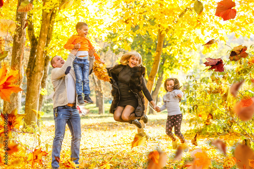 family  childhood  season and people concept - happy family playing with autumn leaves in park