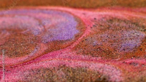 Mixing colors. Fluid magic. Creative painting. Pink orange stream of liquid paint floating and mixing together with glitter in macro shooting.
