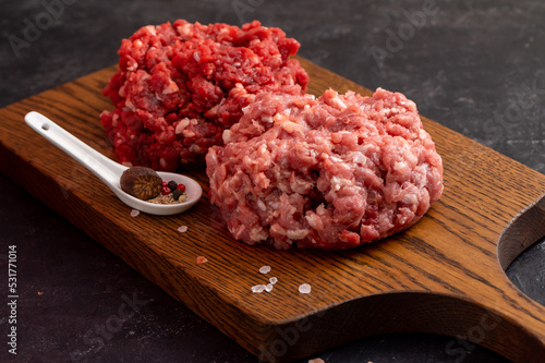 Two Different Balls Of Minced Meat: Beef And Pork Got Placed On A Wooden Board Separately. Culinary Preparation. Hamburger Ingredients. Peppercorns, Coarse Tibetan Salt, Nutmeg. Side View.