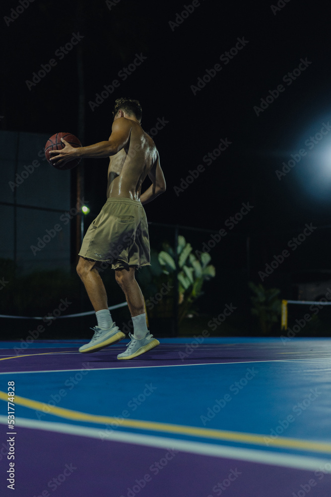 Man friends play basketball in the open area. Night basketball game in the yard.