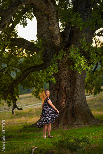 Young Indian plus size woman by a huge tree at sunset