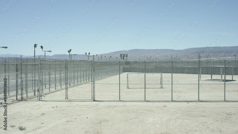 Electric chain-link fence with barbed wire of the prison, High barbed wire fence around prison or secret military base, detention facility, watchtower, last sun rays penetrating Electric chain-link fence with barbed wire of the prison, High barbed wire fence around prison or secret military base, detention facility, watchtower, last sun rays penetrating