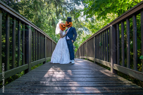 Brautpaar auf einer Brücke mit geschnitzten Kürbis auf dem Kopf. Horror Hochzeit an Halloween.