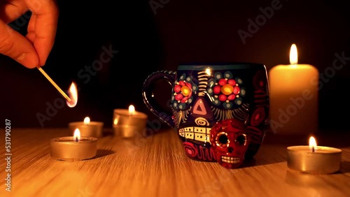 Candle igniting with match by dia de los muertos or day of the dead skull mug photo