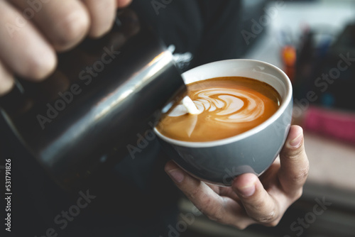 Barista preparing cafe latte, pouring milk into a coffee. Closeup on latte art.