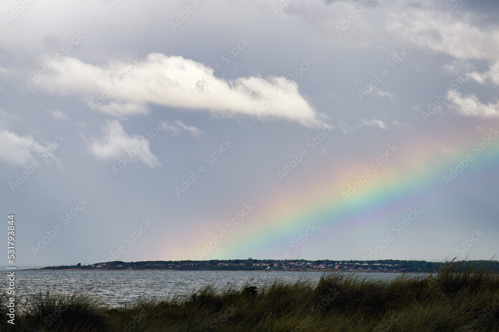 Rainbow after heavy rainfall in Angelholm, Sweden. Magnarp in the background. Selective focus.