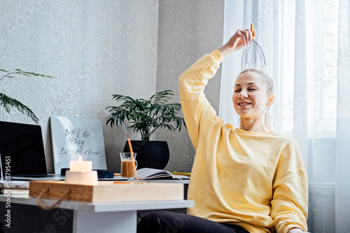 Foto Woman on workplace with Head Massager Scalp Scratcher with Fingers