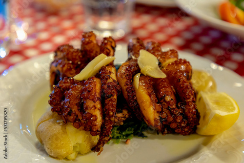 Selective focus of roasted octopus severed with potatoes and lime in white plate, Polvo a lagareiro is one of the most appreciated traditional Portuguese dishes, Delicious Portugal food in the summer. photo
