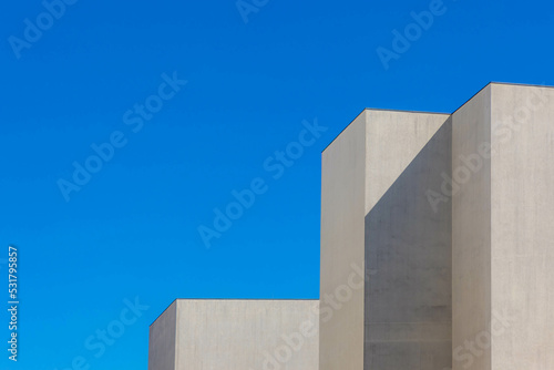 Minimalist photography with gromit building concrete building under blue clear sky, White grey geometric cement pole in minimalist, Modern architecture background.