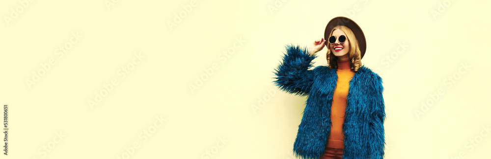 Fashionable portrait of stylish happy smiling young woman, female model posing wearing blue faux fur, round hat on white background Fashionable portrait of stylish happy smiling young woman, female model posing wearing blue faux fur, round hat on white background