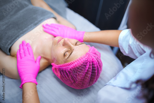 Attractive female at spa health club getting a facial massage. Beautician doing massage of face, neck and shoulders ofbeautiful young woman at luxury beauty salon