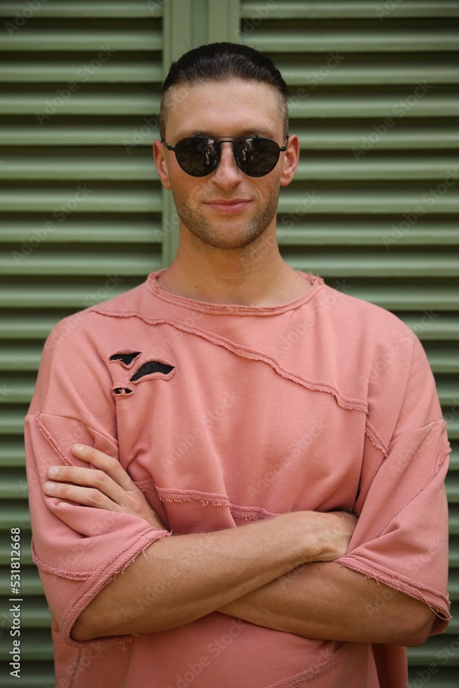 Handsome young man in stylish sunglasses near shutters Handsome young man in stylish sunglasses near shutters