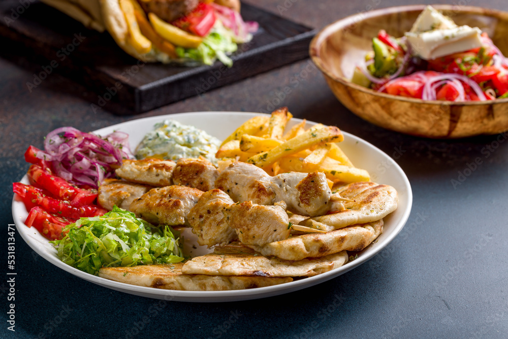 souvlaki with chicken vegetables and pita, greek salad with feta and pita gyros with beef patty and vegetable on dark stone table, selective focus, macro close up