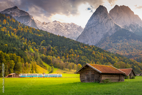 Obraz na płótnie Train in Bavarian alps at autumn and wooden barns at sunset, Garmisch, Germany w salonie