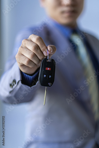 Holding car keys Asian businessman in classic gray shirt suit isolated on gray wall background studio photo. career success wealthy business business idea