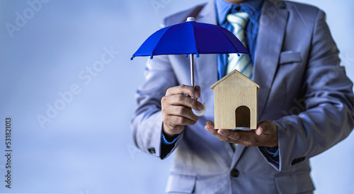 Home and real estate insurance ideas, individuals holding small umbrellas and sample homes. Home insurance for upcoming losses and fires building fire insurance